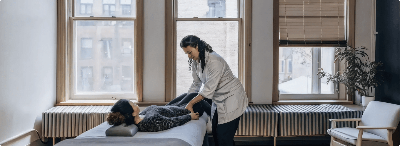 A Physio-Logic clinician treating a patient on a table in a sunlit Brooklyn treatment room