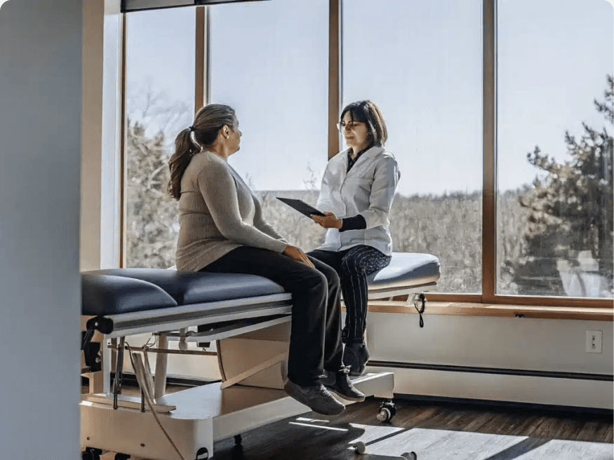 A physical therapist guiding a patient through a gentle core and breathing exercise on a treatment table