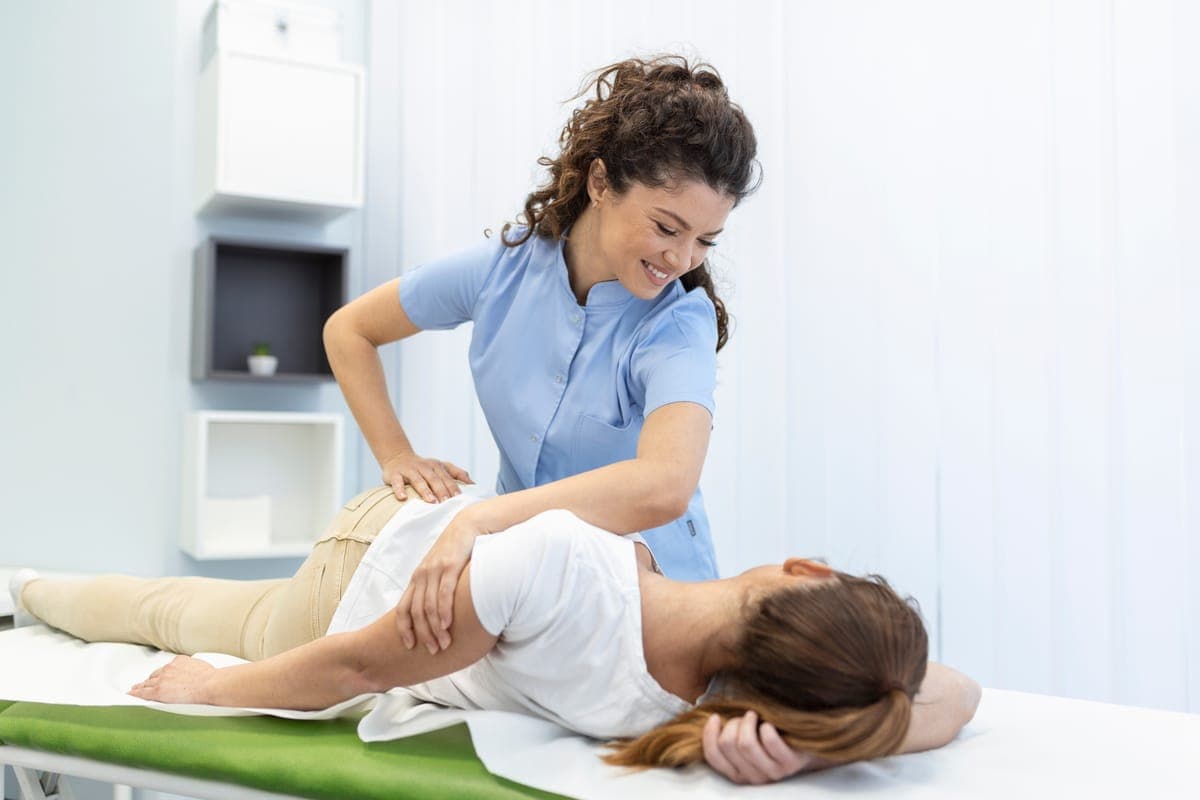 A chiropractor guiding a patient through a side-lying spinal mobilization on a treatment table