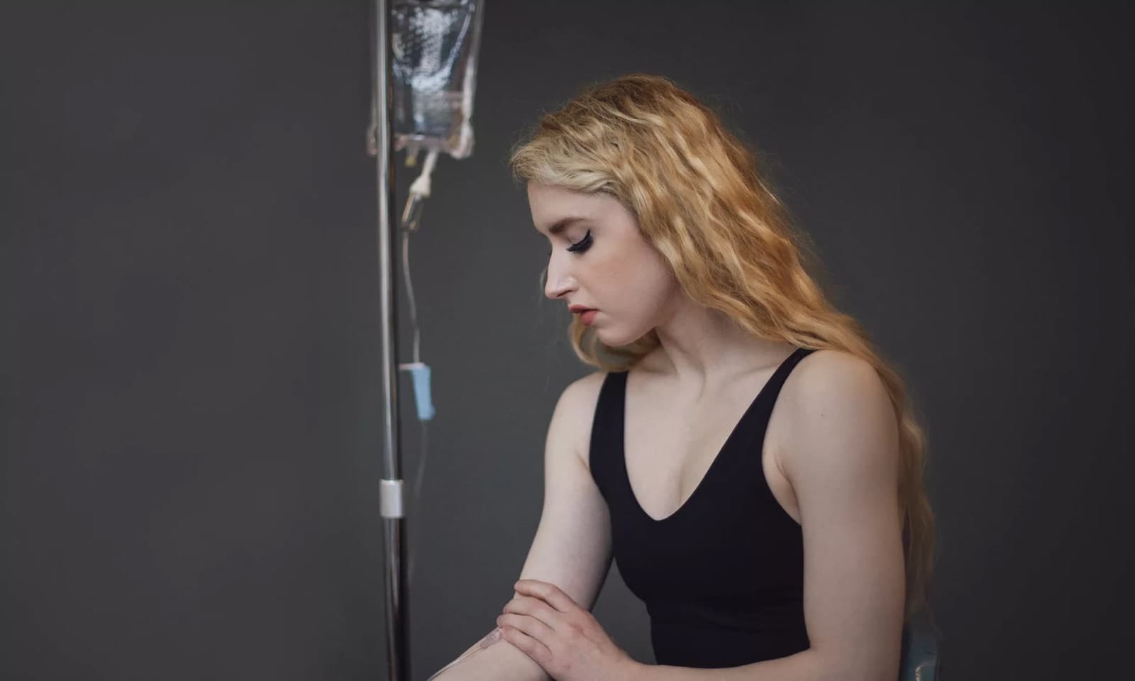 A patient seated beside an IV drip stand during a vitamin infusion session