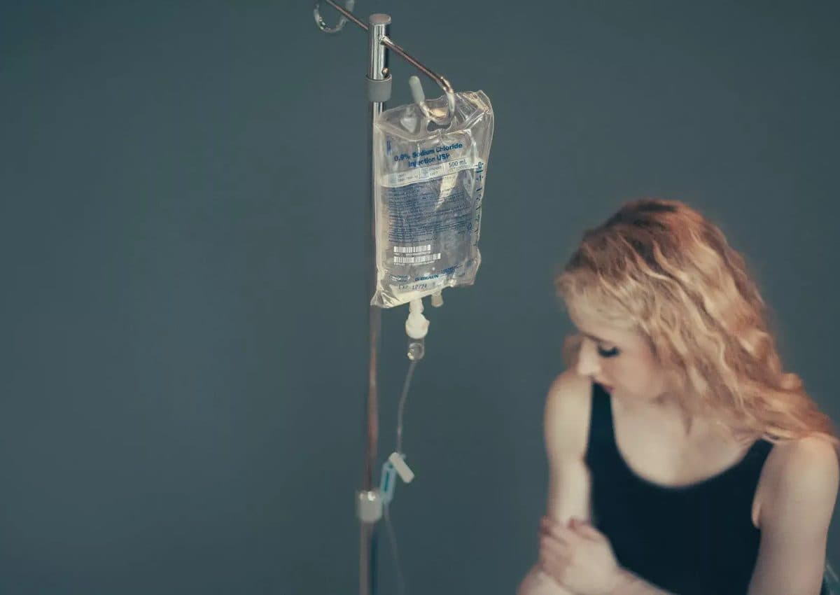 An IV drip bag hanging beside a patient receiving vitamin infusion therapy
