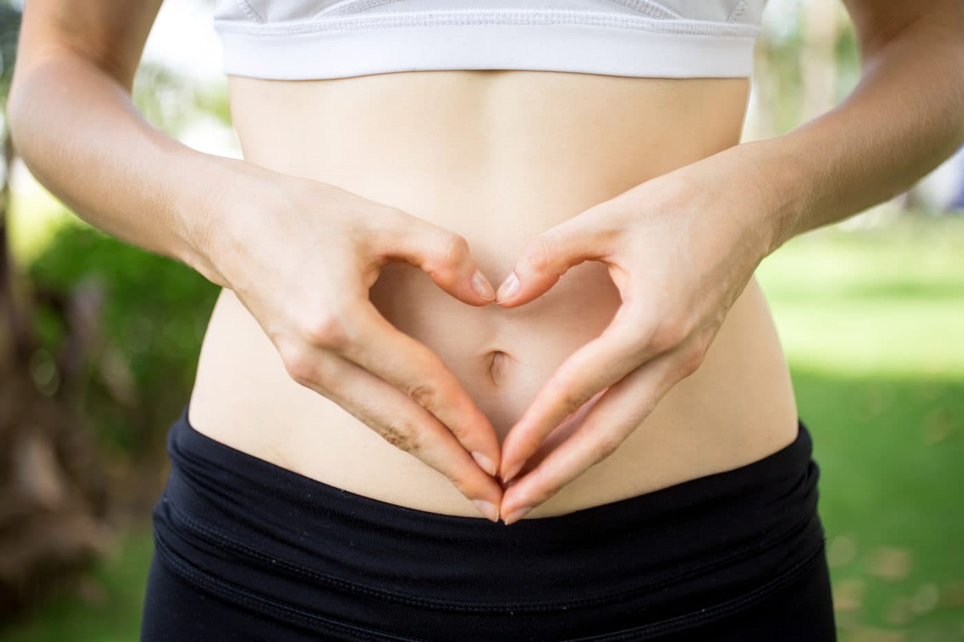 A person resting both hands in a heart shape over their midsection
