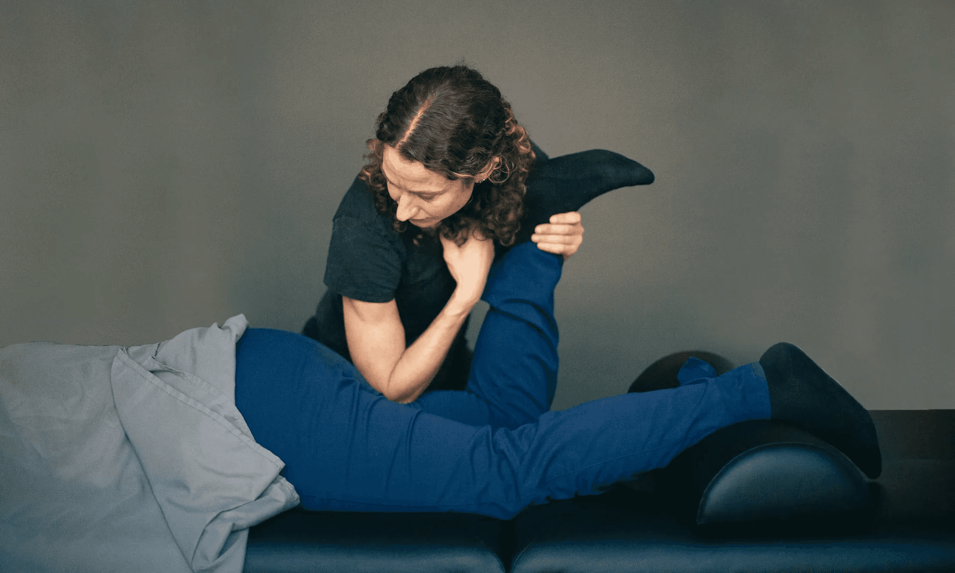 A therapist bending a side-lying patient's knee toward the chest while working into the hip