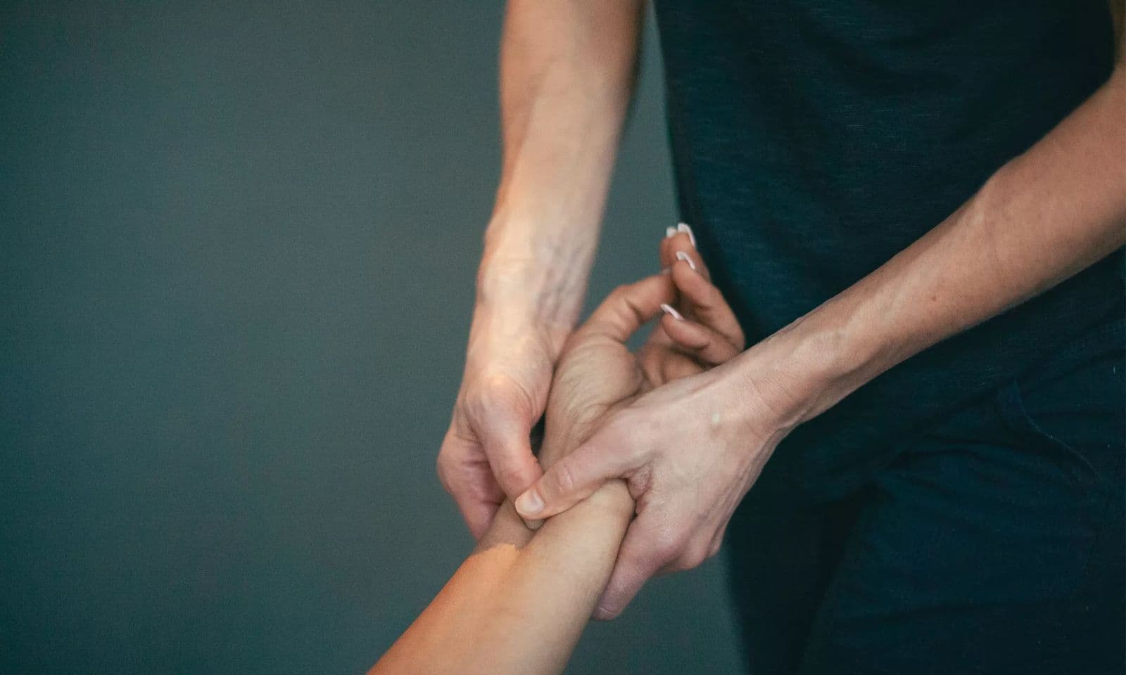 A therapist pressing with both thumbs into a point on the inside of a patient's forearm