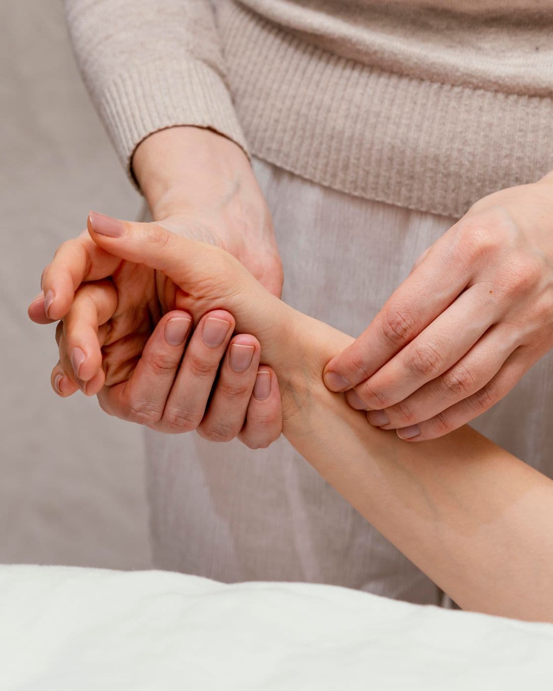 Close view of a therapist supporting a patient's hand while pressing a point on the inside of the wrist