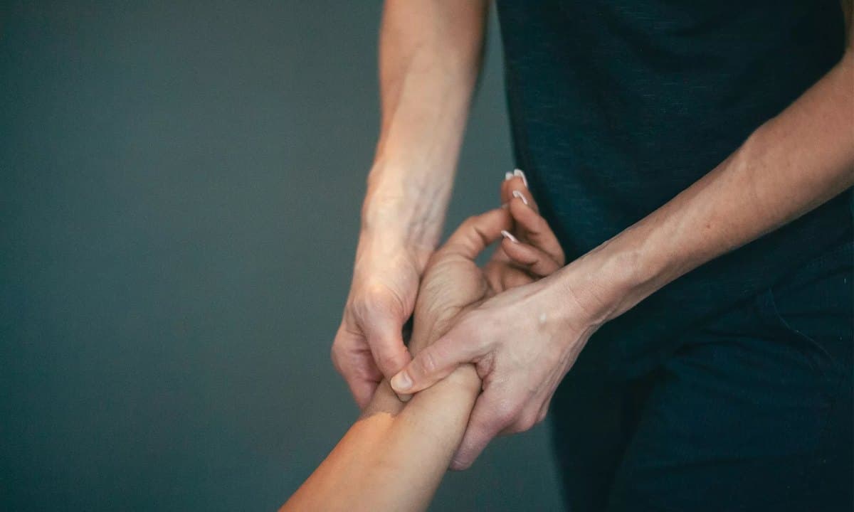A therapist pressing with both thumbs into a point on the inside of a patient's wrist