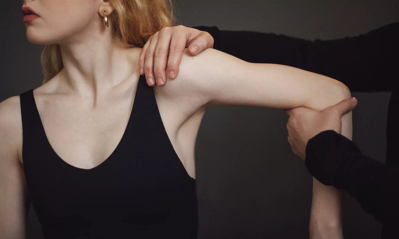 A clinician supporting a patient's shoulder and forearm while guiding her arm through its range of motion