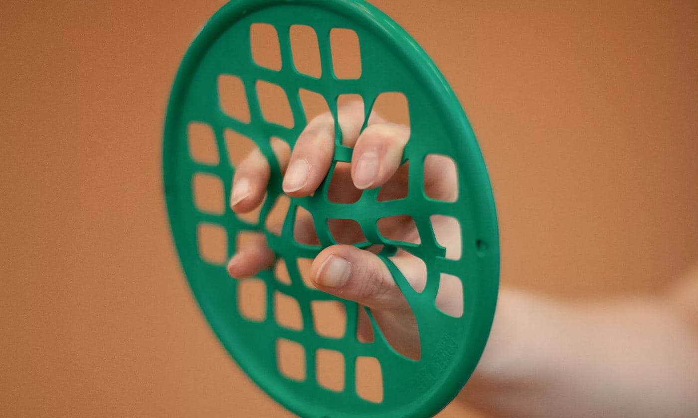 A patient working their fingers through a green hand-therapy resistance web