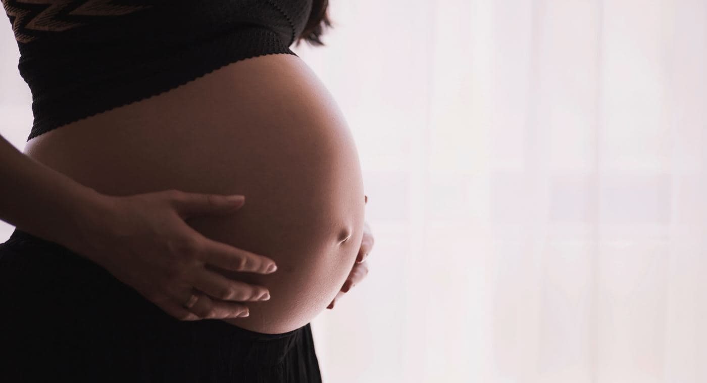 A pregnant patient resting a hand on her abdomen during a therapy session