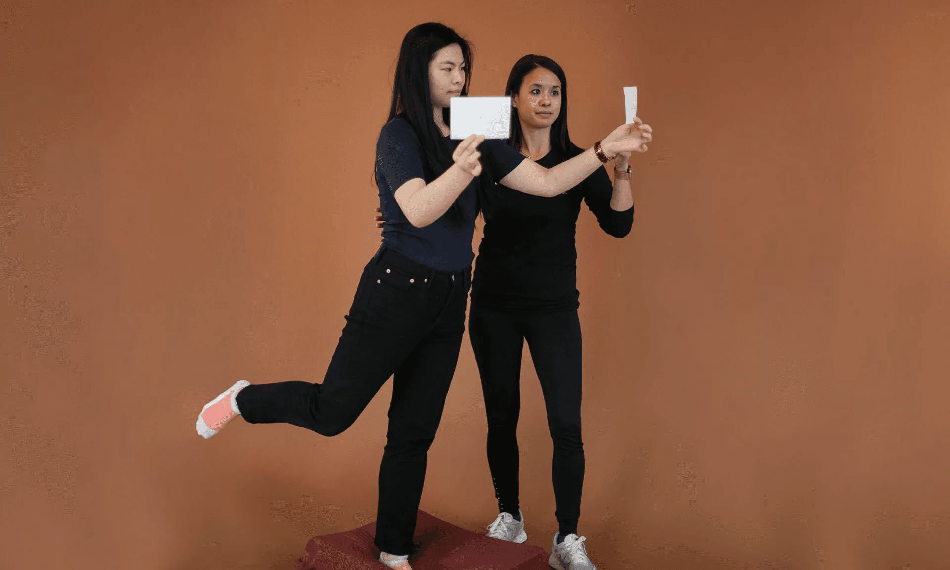 A patient balancing on one leg on a cushion while a therapist holds visual targets at eye level