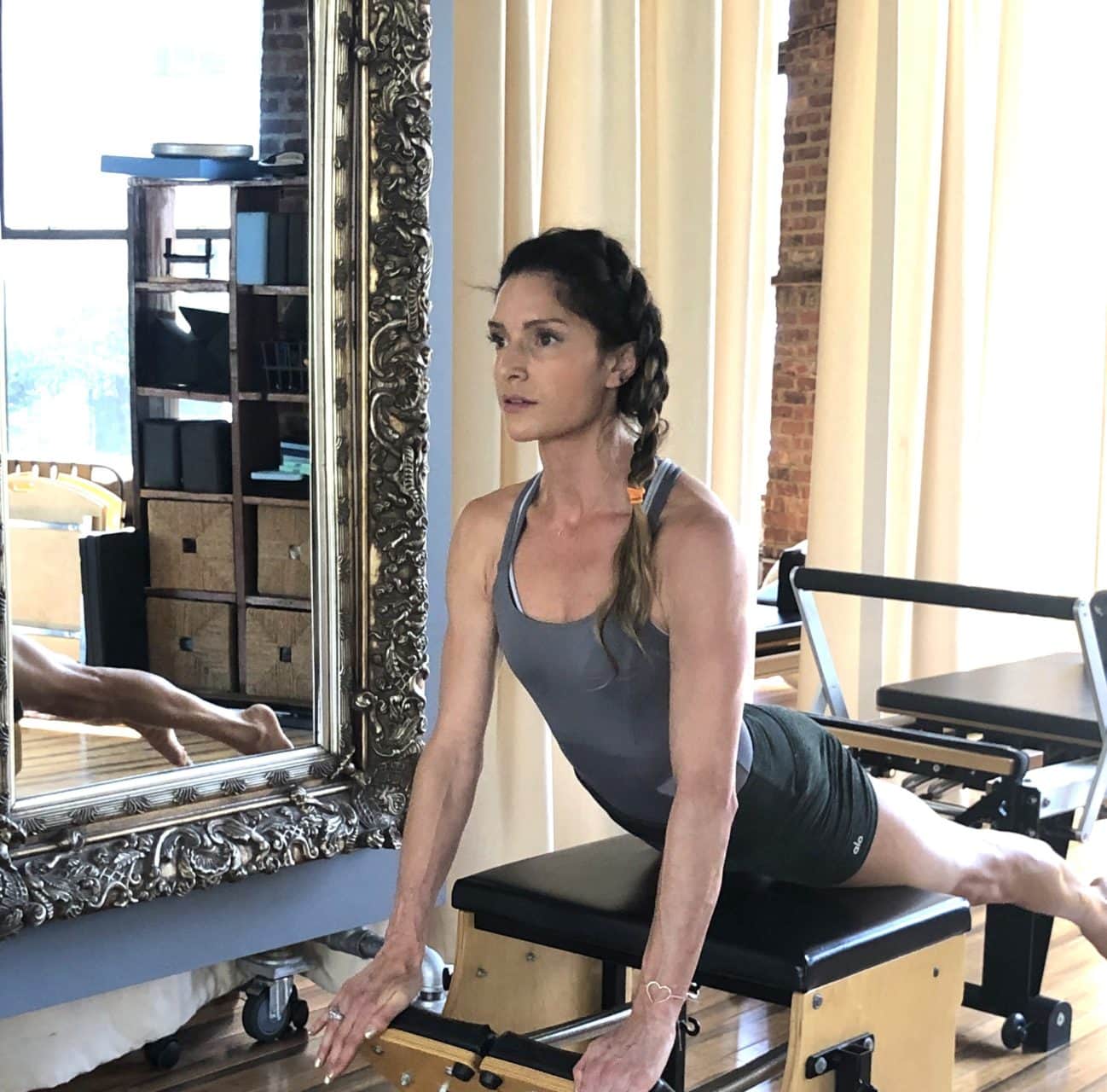 A woman working on a Pilates reformer in a bright studio