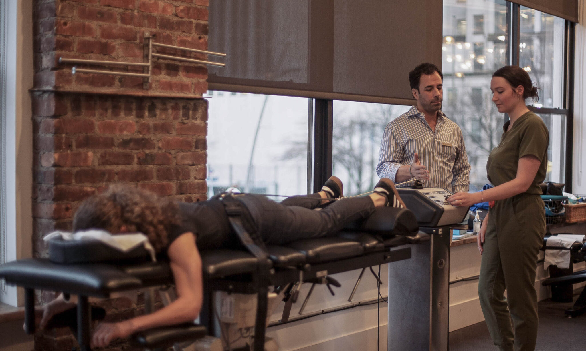 Chiropractor explaining spinal decompression machine to patient during chiropractic care session in Brooklyn clinic.