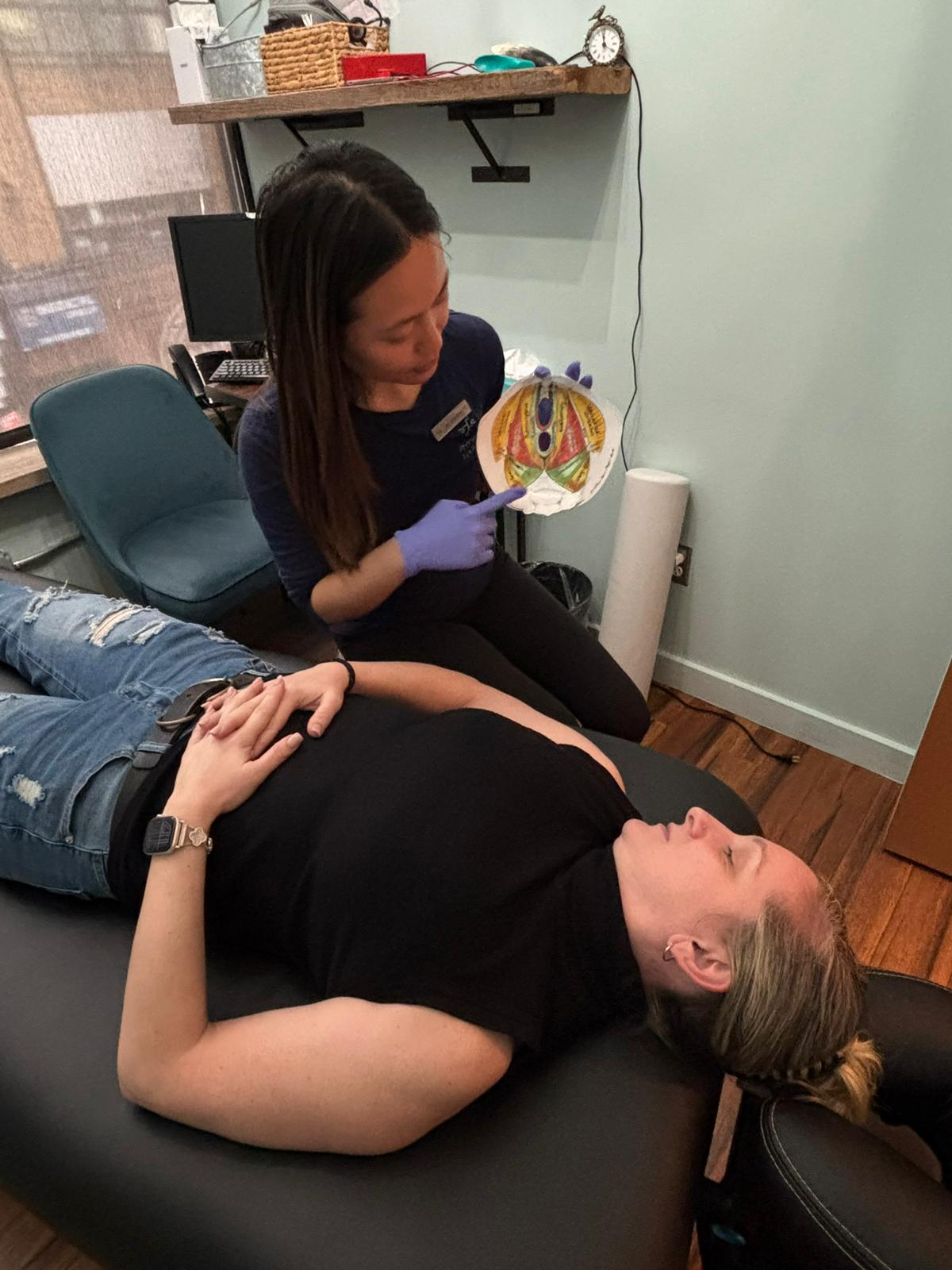 Pelvic floor physical therapist in NYC explaining pelvic anatomy to a patient lying on a treatment table